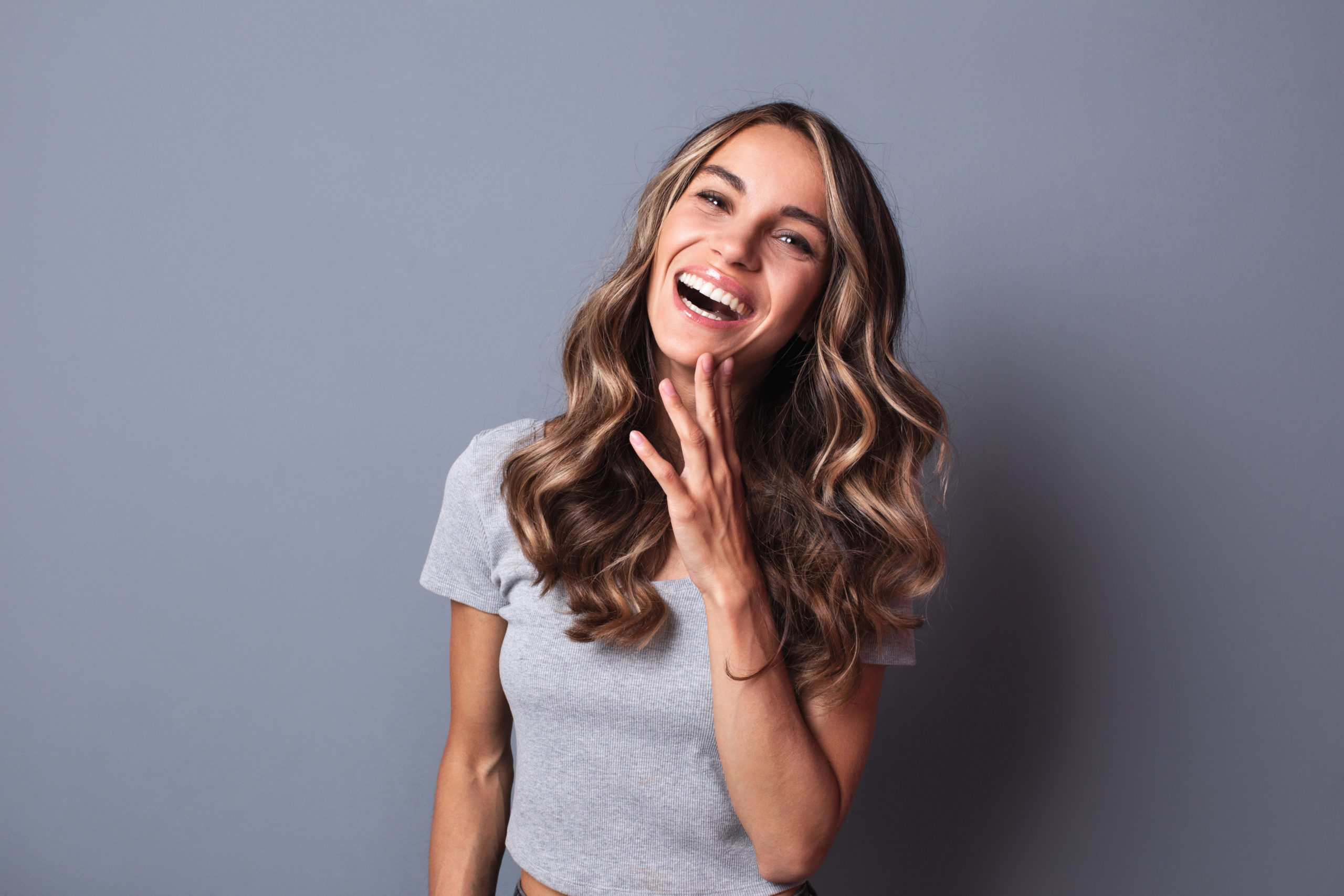 Smiling woman on grey wall background.